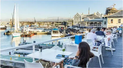 customers sitting at simple tables and chairs on a wooden deck overlooking the harbour, an immaculate setting even amongst the restaurants in waterfront