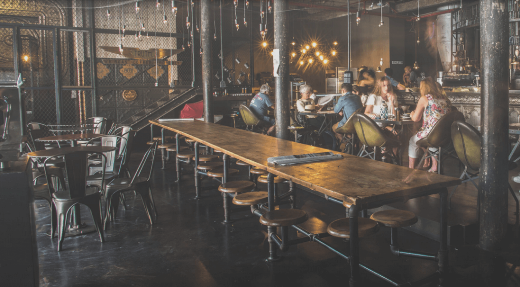 Industrial styled cafe with tables and chairs constructed of metal pipes and wood tops, a great experience for breakfast Cape Town has to offer