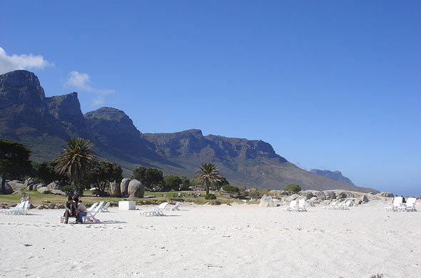 white sandy beach, with sun loungers arranged about it, mountains in the background, an example of the many fine Cape Town beaches available