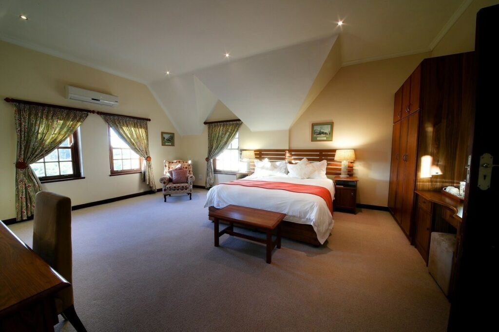 A large spacious room with a double bed, vanity stand, closet, desk with chair, and reading chair, the room is well decorated ensuring you have a great stay at this Paarl accommodation