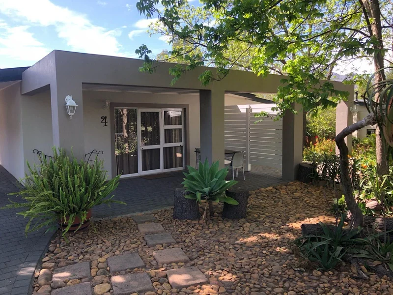 Beautifully kept garden, with a brick path leading to the unit of this Paarl accommodation, with a patio with a table and chairs