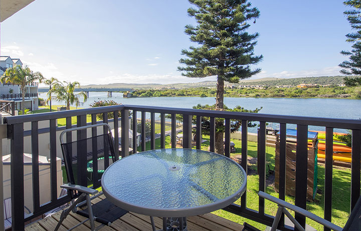 A gable and chairs on a deck, overlooking an activity area and the river beyond it, another great accommodation at Mossel Bay