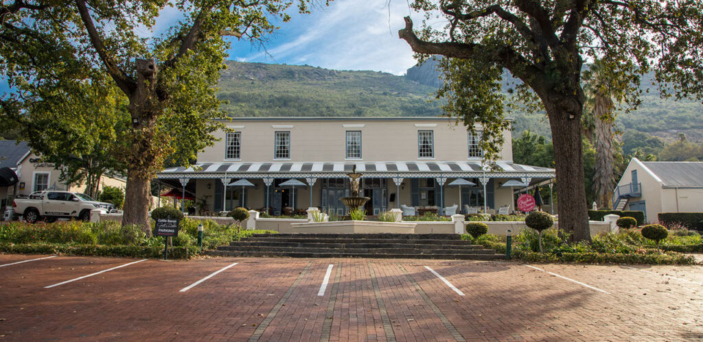 The main building of this Paarl accommodation, with a beautiful water feature in front of it, and the mountains standing majestically behind it