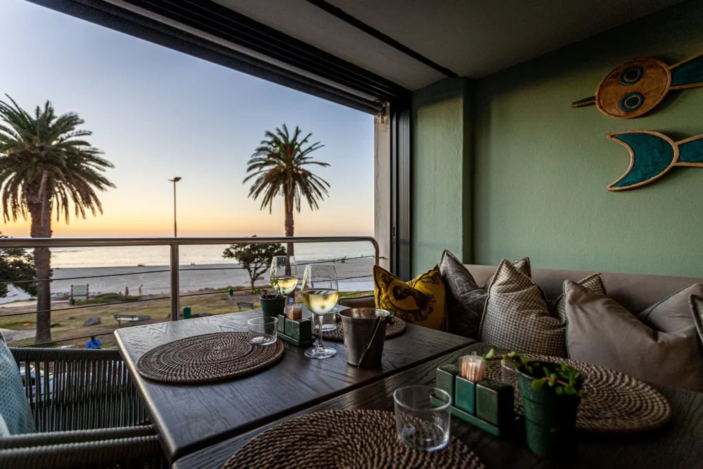 A relaxed dining area at this restaurant in Camps Bay, with sofa and tables overlooking the beach and ocean