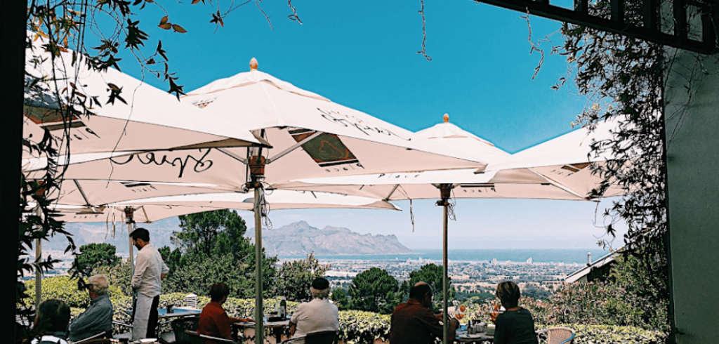 The outdoor seating of this Somerset West restaurant with stunning views of the ocean in the distance